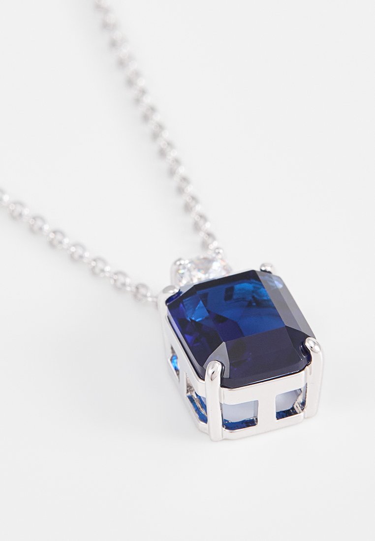 Quadratisch geschnittenes blaues Edelstein-Pendant in silberner Fassung, das ein filigranes Durchbruchsdesign und eine zarte Kette aufweist.