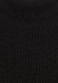 Pull à col roulé noir en tricot avec une texture côtelée, présentant un col haut et une coupe ajustée. Fabriqué à partir d'un tissu doux et chaud.