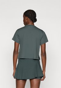 Szürke sportfelső rövid ujjal, egy hozzá illő bővülő szoknyával párosítva. Mindkettő könnyű, elasztikus anyagból készült.