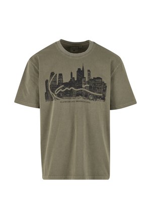Camiseta de algodón verde oliva con un gráfico de un skyline negro y el texto "Flatbush Ave Brooklyn NYC." Mangas cortas, cuello redondo.
