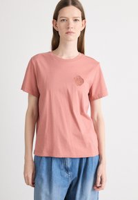 Rosa bomull T-skjorte med korte ermer og rund hals, med et sirkulært preget design på venstre bryst.