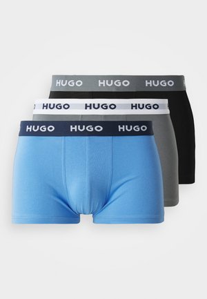 Drie paar boxershorts in blauw, grijs en zwart. Elk paar heeft een merk-elastische tailleband met het woord "HUGO" in contrasterende kleuren.