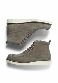 Stivali alla caviglia in suede grigio con lacci frontali, colletto imbottito e suola in gomma bianca. Presentano cuciture decorative e pull tab sul tallone.
