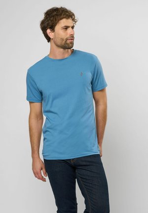 Blå kortærmet T-shirt i blødt bomuld med rund hals og subtilt logo på venstre bryst. Kombineret med mørke jeans.
