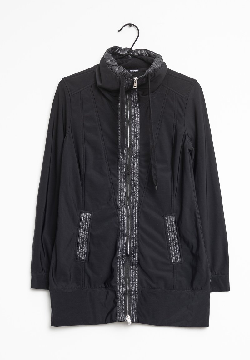 Veste noire à manches longues avec fermeture éclair, col montant, cordons de serrage, bordure texturée le long de la fermeture éclair et des poches, suspendue à un cintre noir.