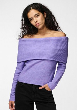 Pull violet à épaules dénudées avec col côtelé et manches longues, en tissu doux, associé à un pantalon noir.