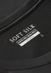 Černá tkanina s hladkým povrchem, se štítkem, na kterém je napsáno "Soft Silk Intimissimi Uomo L." Límec má zaoblený tvar s viditelným švem.