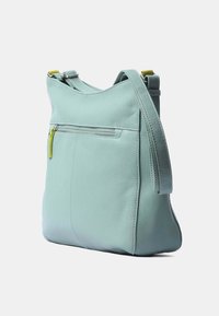 Mintgrön läder crossbody-väska med en dragkedjeficka, justerbar rem och slät yta. Har en minimalistisk design och rundad form.