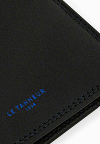 Portafoglio in pelle nera con superficie testurizzata, logo blu e cuciture a contrasto. Design compatto con bordi curvi.