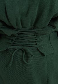 Grüner Strickstoff mit gerafftem Taillendesign, mit einer gerafften Textur und gebundenem Akzent. Weiches, geripptes Material mit glatter Oberfläche.