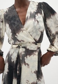 Rochie tip wrap din material ușor; prezintă modele tie-dye în nuanțe de negru, alb și maro; textură pliată; mâneci lungi cu volum și talie legată.