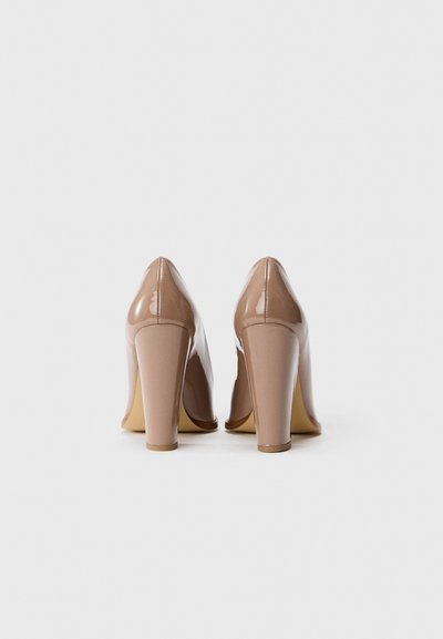 Nude patent leather high heels with a tapered toe and a chunky heel. Smooth texture with a glossy finish and minimal stitching details.