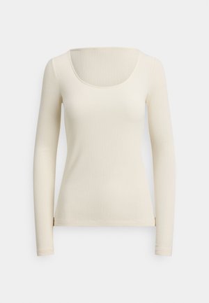 Top a maniche lunghe a coste color crema, con scollo ampio a giro, texture morbida, silhouette aderente e spacchi laterali sull'orlo.