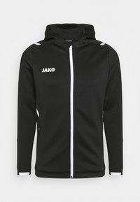 Zwarte capuchonjack van textiel, met een witte rits en accenten, voorzien van het "JAKO" logo op de linkerborst en zijzakken.
