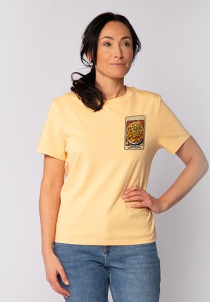 Gelbes T-Shirt mit kurzen Ärmeln, das einen Grafikdruck von Nachos auf der linken Brustseite zeigt. Hergestellt aus weichem Baumwollstoff mit glatter Textur.