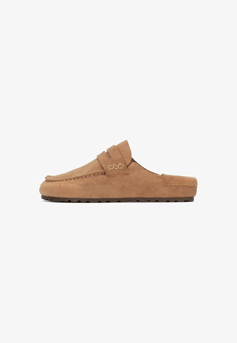 Chaussons en daim marron à enfiler, avec un bout rond, une couture décorative et une semelle en caoutchouc profilée comportant de petits picots antidérapants.