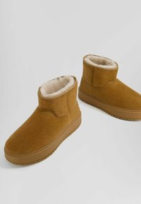 Bruna mocka ankelskor med tjocka gummisulor och plyschbeige pälsfoder inuti för värme och komfort.