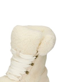 Roomkleurige laars met een fleece buitenkant, dikke boord, witte veters en metalen oogjes. Heeft een gevoerde kraag voor comfort en warmte.