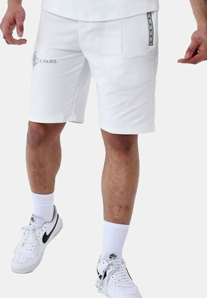Bermudas deportivas blancas fabricadas en un tejido suave, con dos bolsillos laterales, uno de ellos con un acento de marca, y un corte recto hasta la rodilla.