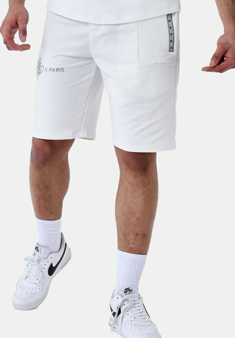 Bermudas deportivas blancas fabricadas en un tejido suave, con dos bolsillos laterales, uno de ellos con un acento de marca, y un corte recto hasta la rodilla.