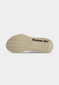 Μπεζ σόλα παπουτσιού Reebok με υφασμένα μοτίβα πρόσφυσης και μαύρο λογότυπο Reebok σε απλό λευκό φόντο.