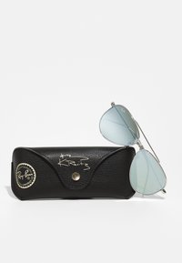 Ray-Ban aurinkolasit hopeakehyksillä ja vaaleansinisillä linsseillä, mukana musta nahkakotelo, jossa on kullanvärinen logo ja allekirjoitus.
