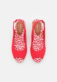 Scarpe slingback rosse con punta aperta, superiore in tessuto e soletta decorata con un motivo rosso e bianco. Cinghia regolabile per una vestibilità sicura.