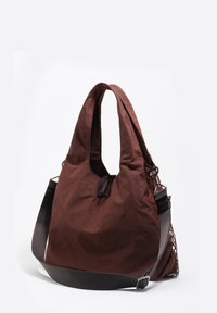 Brązowa, lekka torba materiałowa o miękkim kształcie, z otwartym górnym otworem i odpinanym paskiem na ramię; posiada teksturowaną siateczkową kieszeń.