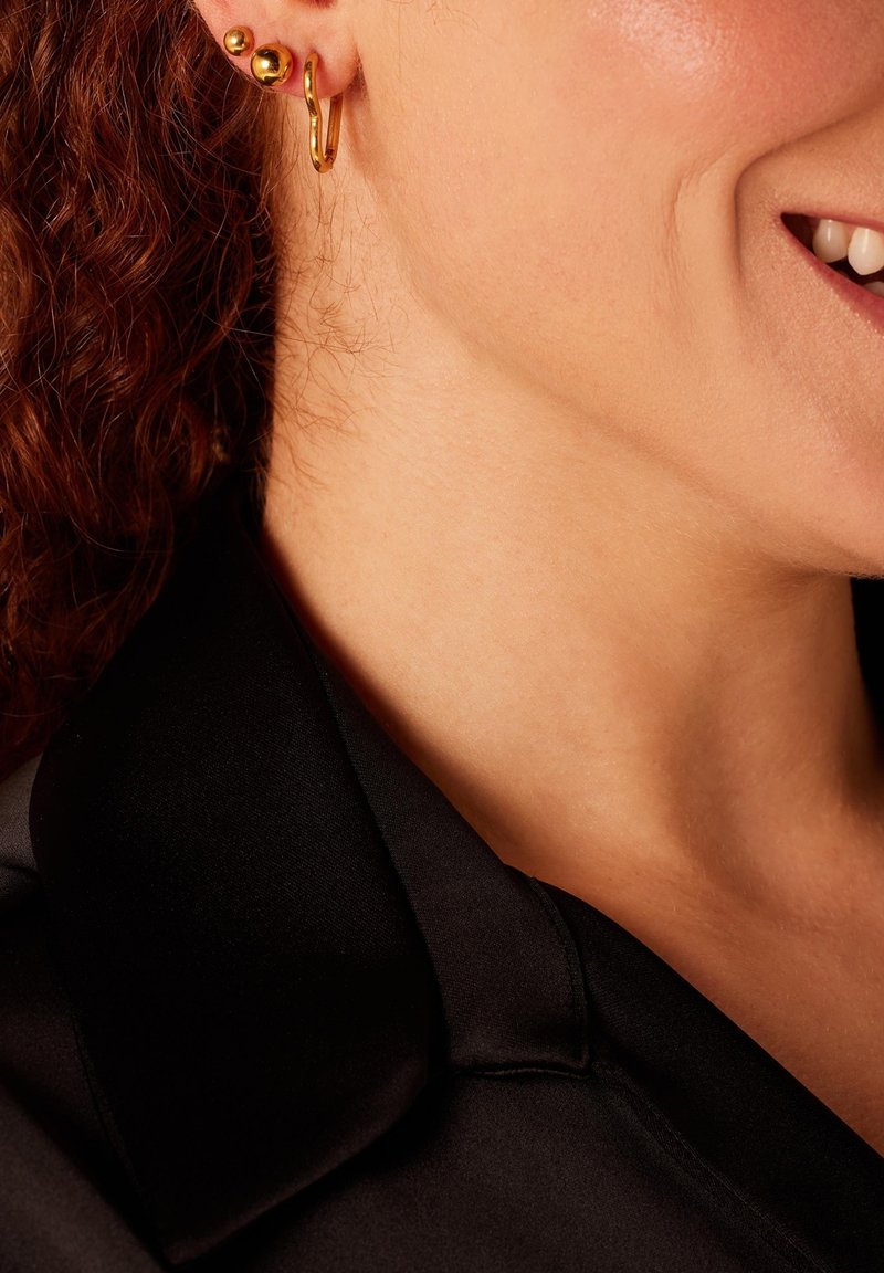 Gouden hoepel- en studoorbellen, met ronde bollen en een open ontwerp. Geleverd met een gestructureerde, gepolijste afwerking, tegen een zwarte satijnen kraag.