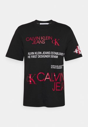 Czarna koszulka z krótkim rękawem z czerwonymi i białymi logo oraz napisem Calvin Klein Jeans nadrukowanymi z przodu i na lewym rękawie.