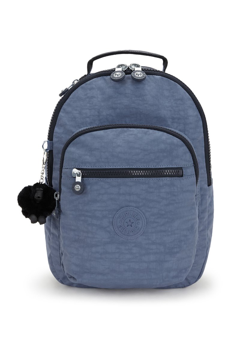 Blå nylonryggsäck med texturerad yta, framficka med dragkedja, rund logotyp-patch, dubbel dragkedjestängning och en svart fluffig charm som accent.