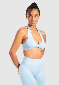 Reggiseno sportivo azzurro chiaro con un design a frontale attorcigliato, abbinato a leggings a vita alta dello stesso colore, caratterizzati da una texture liscia e elastica.