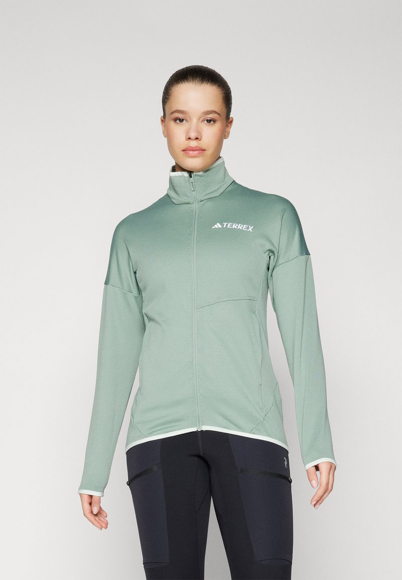 Svijetlozeleni zip-up sako od mekog materijala, s visokim ovratnikom i zip zadnjim džepovima, bijelim akcentima i logotipom "Terrex".