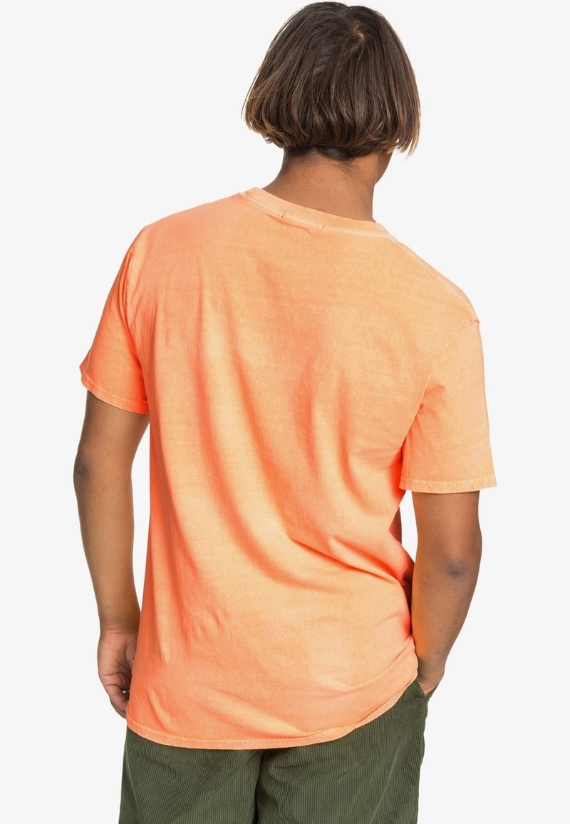 T-shirt orange à manches courtes en tissu doux, coupe décontractée, avec un col rond. Détail de couture visible au niveau de l'encolure et de l'ourlet.
