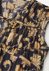 Robe bleu marine foncé avec un motif floral paisley jaune et orange, en tissu léger, avec des manches volantées et un détail de taille froncée.