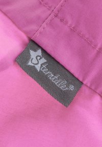 Rosa Stoff mit einer glatten Textur, der ein graues Etikett mit weißem Text und einem Sternlogo zeigt, das in eine Naht genäht ist.