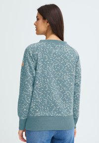 Sinine-roheline mustriline pusa heledate beežide ringjate mustritega, soonikkoes mansettide ja äärega. Pehme tekstuur, ümara kaelusega, käel logomärgiga.