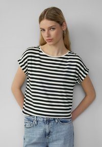 Schwarz-weiße gestreifte Kurzarm-T-Shirts mit Rundhalsausschnitt aus weichem Stoff, kombiniert mit hellblauen Jeansshorts.