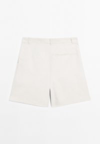 Shorts blancs sur mesure avec passants de ceinture et une poche passepoilée à l'arrière, présentés à plat sur un fond blanc.
