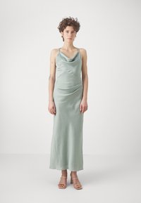 Satingröna kvällsklänning med en cowl-krage, tunna axelremmar och en figurnära silhuett med draperade detaljer över midjan.