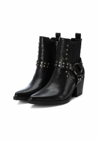 Botines negros con puntas afiladas, hechos de cuero, con tachuelas plateadas, una correa y un tacón cuadrado. Panel elástico texturizado en los laterales.