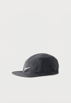 Black Nike cap with white swoosh logo, structured crown, and flat brim, set against a plain light background.