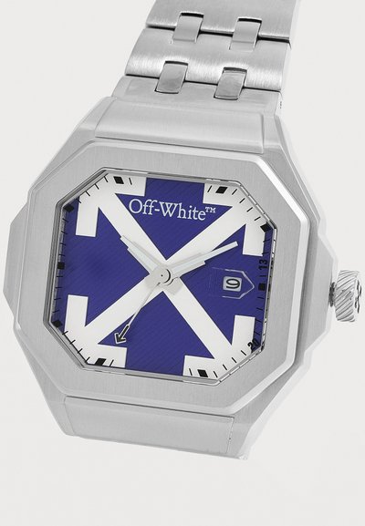 Montre-bracelet en métal argenté avec boîtier octogonal, cadran bleu présentant un motif de flèche blanche, marquage Off-White et affichage de la date à trois heures.