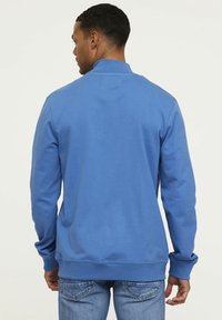 Sweatshirt bleu à manches longues, col montant et poignets côtelés. Fabriqué en matériau doux, avec une texture lisse et sans motifs visibles.