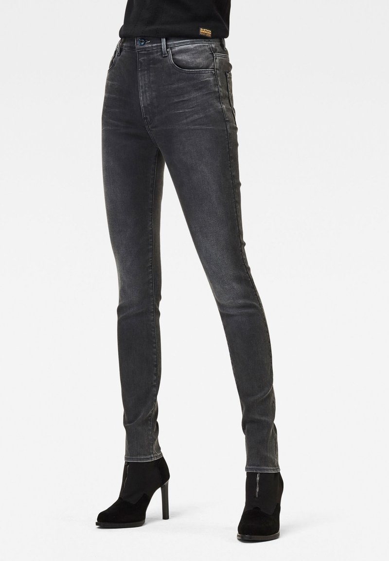 Jeans ajustados en denim gris oscuro con un acabado descolorido, que presentan un diseño clásico de cinco bolsillos y detalles de costura sutiles a lo largo de los lados.