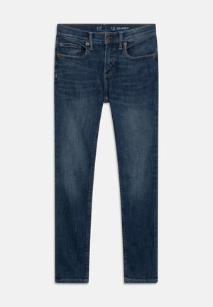 Jeans ajustados de mezclilla de color azul oscuro, con un diseño clásico de cinco bolsillos, botón de metal y áreas sutilmente desgastadas en la tela.