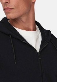 Navy zip-up hoodie with drawstring, soft texture, and a white crew neck T-shirt underneath, highlighting a clean, casual look.