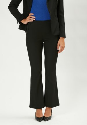 Zwarte flared pants met een gladde textuur, voorzien van zijknopen en een hoge taille, gecombineerd met een blauwe geribbelde top en zwarte hakken.