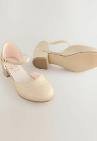 Kuldne sädelev kleitjalats, millel on ümmargune nina, pahkluuring ja madal plokk-kõrgus. Sile sisemine vooder ja tekstureeritud kummitald.