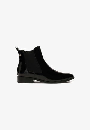 Bottines Chelsea en cuir verni noir avec panneaux latéraux élastiques, bout pointu, petit talon carré, et une languette pour un enfilage facile. Accent doré sur le talon.